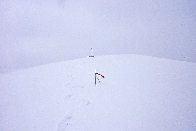 山頂に立つ赤旗・地吹雪。